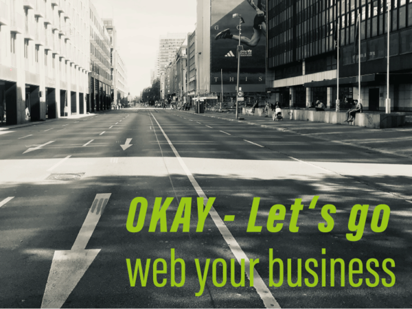 A quiet city street with buildings on either side. The road has directional arrows pointing forward. Text overlay reads, "OKAY - Let's go web your business" in bold green letters. The image is presented in a black and white filter, creating a calm atmosphere.